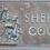 Bronze plaque with the text "sheriff court" beneath a relief of a coat of arms flanked by two heraldic beasts.