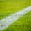 Close-up of a white boundary line on a lush green soccer field.