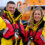 Two lifeboat crew members in yellow rnli jackets smiling in front of a lifeboat.