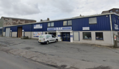 Industrial building with a sign reading "d.i.t.t." and a white van parked in front.