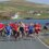 Group of runners competing in a marathon on a rural road, with houses and hills in the background.