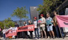 People are standing in front of an Equinor building, holding signs and banners with messages including "STOP BAY DU NORD" and "#EQUINOROUT" in a protest.