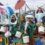 Group of people in ocean-themed costumes holding buckets stand on a decorated float.