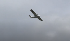 A white, single-engine airplane is flying in a cloudy sky.