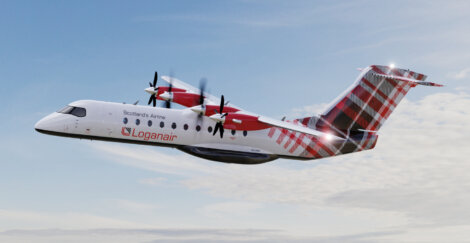 A Logan Air aircraft with tartan tail design is mid-flight against a partly cloudy sky. The plane's propellers are in motion.