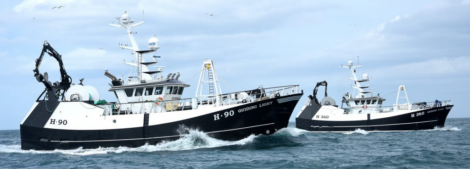 Two fishing boats, H-90 and H-360, navigate through the ocean under a cloudy sky.