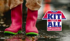 Child in pink boots stands in a puddle. Text on the right reads "Kit For All #PassItOn" with a t-shirt graphic.