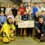 A group of children and adults posing indoors with a large novelty check for the Royal National Lifeboat Institution (RNLI).