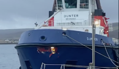 A large blue and white boat named "Dunter" is docked at a pier on a cloudy day.