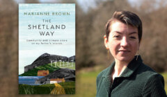 A woman stands outdoors next to a book titled "The Shetland Way" by Marianne Brown, with a subtitle about community and climate crisis on Shetland Islands.