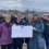 A group of people stands on a dock in front of a lifeboat, holding a large cheque for £3,500 made out to RNLI Lerwick.