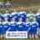 A co-ed sports team in blue and white uniforms poses for a group photo on an outdoor field with four adults and a sponsorship banner; inset shows headshots of four players.