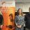Three people stand indoors next to a Warmworks banner promoting affordable home warmth, with balloons and informational displays in the background.