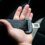 A hand holding an unfastened black seat belt inside a car.